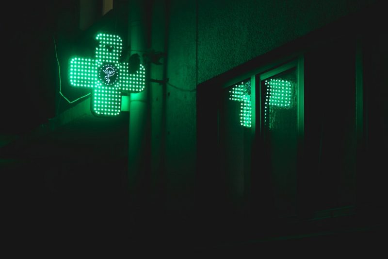 Cruz verde iluminada de una farmacia en plena noche